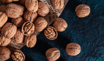 Shelled and unshelled walnuts on dark grunge background. Top view, flat lay with copy space.