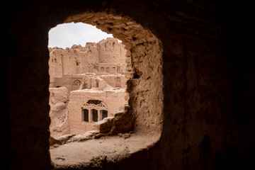 view from a hole in the wall on the ancient city ruins in the desert in iran