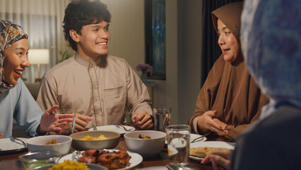 Happy Asia muslim parent and their kids Ramadan dinner together in dining room at home. Family of...