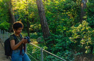 Happy young black African American female photojournalist with dark curly hair checking amazed and...