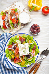 Traditional Greek Food: Greek Salad, Gyros with meat and vegetables, Tzatziki sauce, Olives on White rustic wooden table background top view. Cuisine of Greece
