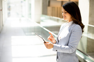 Young woman working on digital tablet in the office hallway