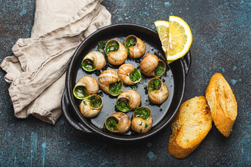 Escargots de Bourgogne Snails with Garlic Butter and Parsley in black cast iron pan with Lemon and...