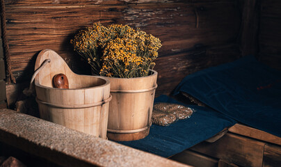 Spa, sauna with stones and wellness center with water bucket, oak brooms, herbs on wooden...