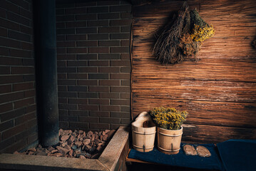 Spa, sauna with stones and wellness center with water bucket, oak brooms, herbs on wooden background. winter wellness concept relaxing and healing therapy.