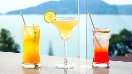 Three different types of blended fruit margaritas cocktails in vibrant colors, summer getaway. Enjoy refreshing cocktails by the hotel swimming pool with sea view at a luxury villa.