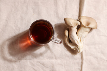 Natural medicine, reduce stress and improve immunity concept. Mushroom hot drink. Tea in glass mug with mushrooms on textile background. Copy space. 