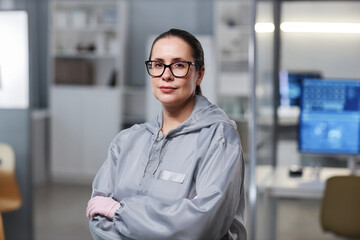 Waist up portrait of woman wearing protective suit in laboratory and looking at camera, copy space