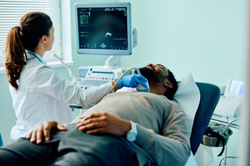 Black man during ultrasound thyroid gland examination at doctor's office.