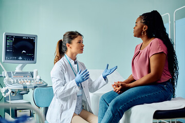 Female doctor talking to black woman during medical examination at the clinic.