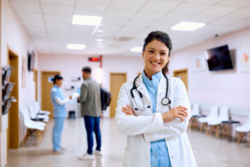 Confident female doctor standing in hallway and looking at camera.