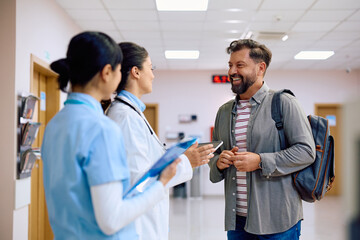 Fototapeta premium Happy man talks to female doctor in hallway of medical clinic.