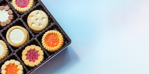 Close-up of various cookies in box on blue background. Butter cookies in assortment. copy space