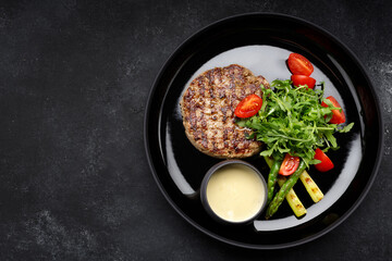 mouthwatering grilled pork steak topped with savory sauce, peppery arugula and ripe tomatoes