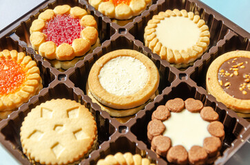 Close-up of various cookies in box. Butter biscuits round in assortment with jam, chocolate, fondant