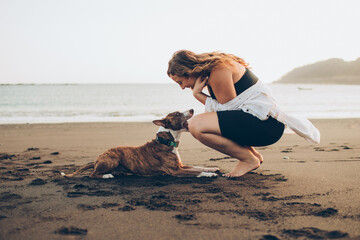 woman petting her dog on the beach