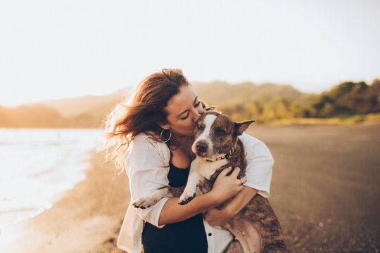woman hugging her dog on the beach