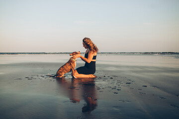 woman petting her dog on the beach