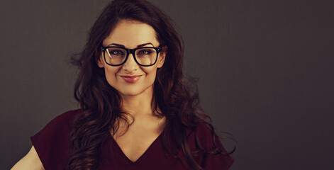 Beautiful thinking happy brunette business woman looking happy in eye glasses and holding spectacles on toned background with empty copy space. Closeup front view  portrait. Vintage bright color