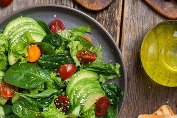 Salad with spinach, avocado, tomatoes in a plate. Vegetarian salad