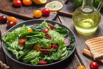 Salad with spinach, avocado, tomatoes in a plate. Vegetarian salad