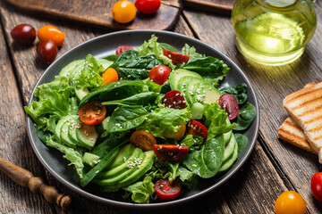 Salad with spinach, avocado, tomatoes in a plate. Vegetarian salad