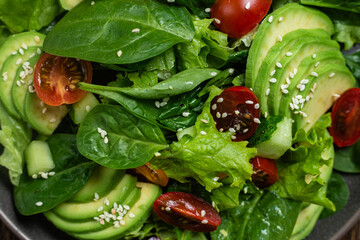 Salad with spinach, avocado, tomatoes in a plate. Vegetarian salad