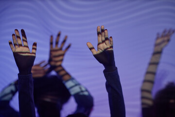 Close up of hands of dancing people at disco party lit by neon lights, copy space