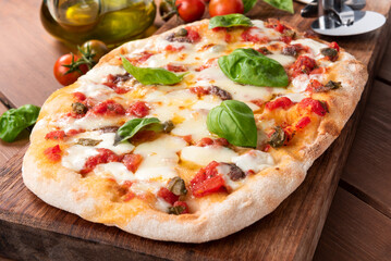 Tipica pinsa romana condita con pomodoro, mozzarella, capperi e basilico fresco, cibo italiano 