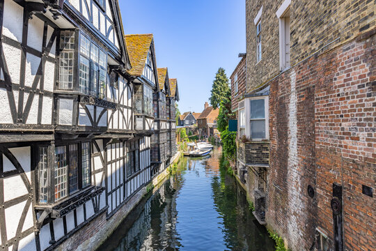 Water channel of Stour river by Canterbury, with tourist boat navigating the river. Typical buildings overlooking the Stour river in Canterbury, Kent, England, UK