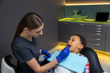 Female doctor checking up dark-skinned boy
