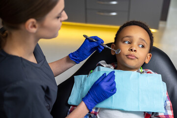 Female doctor checking up dark-skinned boy