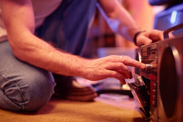 Closeup of young man using casette player at retro house party, copy space