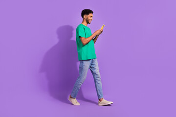 Full size profile photo of positive person hold use smart phone walking isolated on violet color background