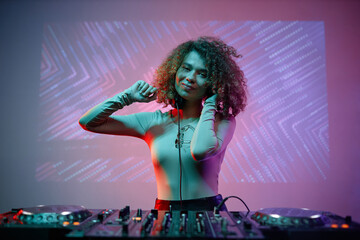 Portrait of young woman as female DJ looking at camera at nightclub, copy space