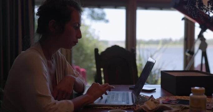 Woman Working From Home On Messy Kitchen Table - Side Profile