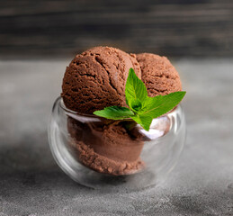 Chocolate ice cream with mint leaves in a glass cup on a gray background