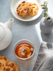 A cup of herbal tea, teapot and homemade cookies on a blue background with morning shadow. Drink concept for breakfast.