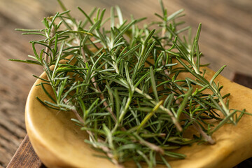 fresh organic freshly picked rosemary with dew or rain drops on top of rustic farmhouse wooden table, selective focus