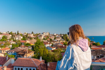 A girl from an observation deck looks at the old town of Kaleiçi in the Turkish city of Antalya. A girl looks at old houses in the popular tourist area of Antalya.