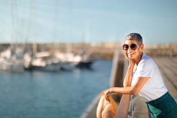 Happy Senior Lady Posing With Sunglasses Standing At Sea Pier