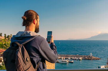 A man tourist takes a picture of the old port in the Turkish city of Antalya with his phone. A...