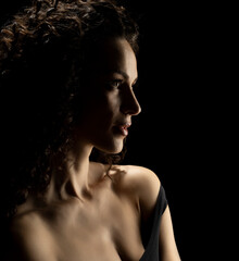 Sensual portrait silhouette of beautiful curly woman in backlight on a black background