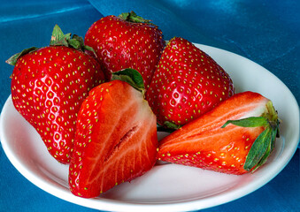 Strawberries cut into pieces on a white plate. Close-up.