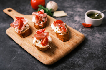 Bruschetta with prosciutto, pesto, mozzarella and tomatoes. Food, restaurant and event concept.