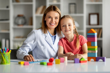 Portrait of happy little girl and child development specialist lady