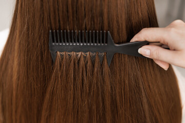 Woman combing long brown gray hair by brush, concept hair health, natural hair care. Hair care. Keratin treatment. Beauty fashion. Professional cosmetics