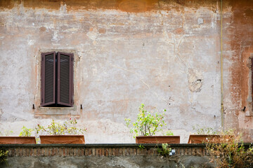 Shuttered window and aged wall with ledge in Rome, Italy