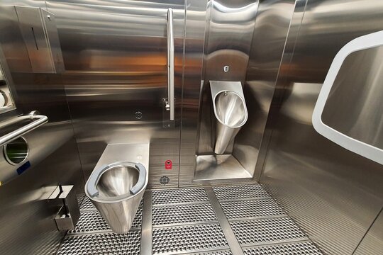 Sanitary metal urinal, toilet bowl in public bathroom with hygienic automatic water saving electronic flush. Urinal with urine sensor. Inductive flush toilet. WC