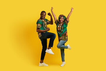 Fototapeta na wymiar Emotional bright african couple celebrating success on yellow